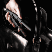 Womens hand Placing WAM Mini straightening Iron into her black handbag 